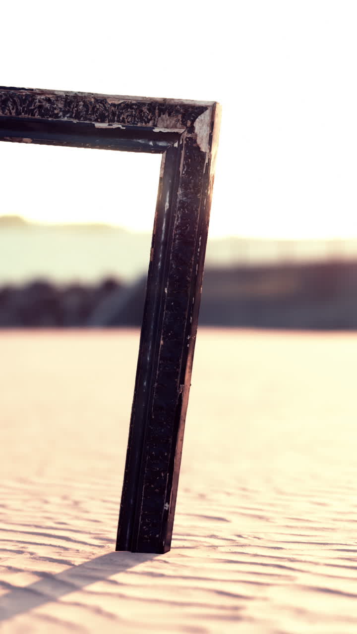 Una struttura in legno si erge solitaria nella sabbia del deserto contro un tramonto dorato
