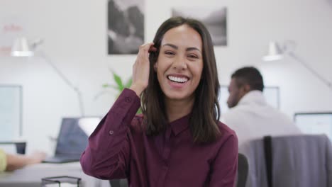 portrait of smiling biracial businesswoman looking at camera in modern office