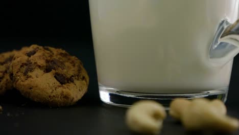 Cerca-De-Un-Vaso-Lleno-De-Leche-De-Avena-Al-Lado-Hay-Galletas-Y-Anacardos