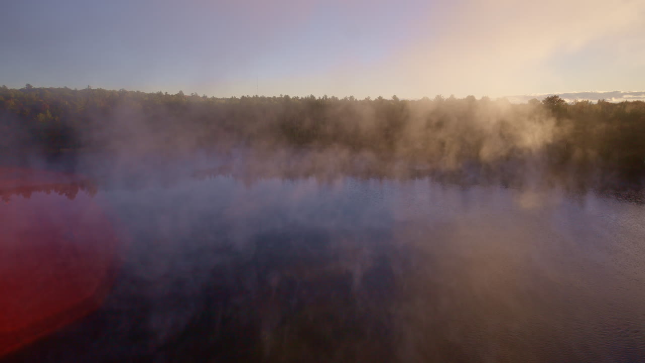 Cinematic drone sweep over water with mist climbing in dawn light