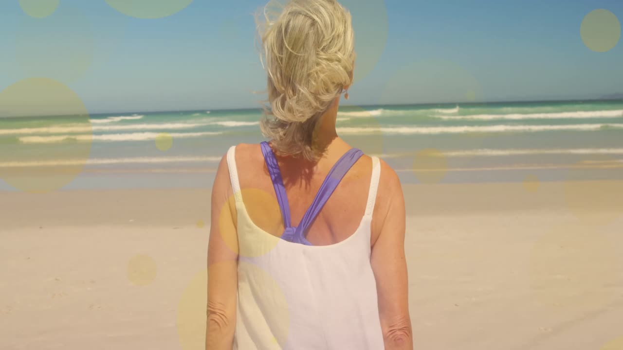 해변에서  ⁇ 고 있는 백인 여성 위의 빛 반점의 애니메이션