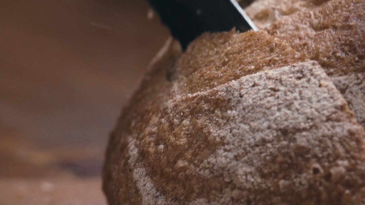 Close-Up of Cutting Loaf of Freshly Baked Artisan Bread with Knife
