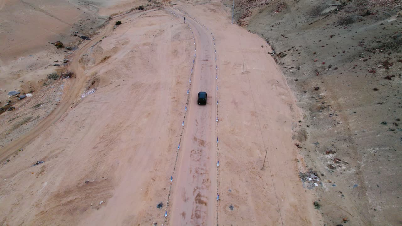 Drone zoom in ascending shot over a winding desert road in Peru, cinematic aerial travel footage at golden hour