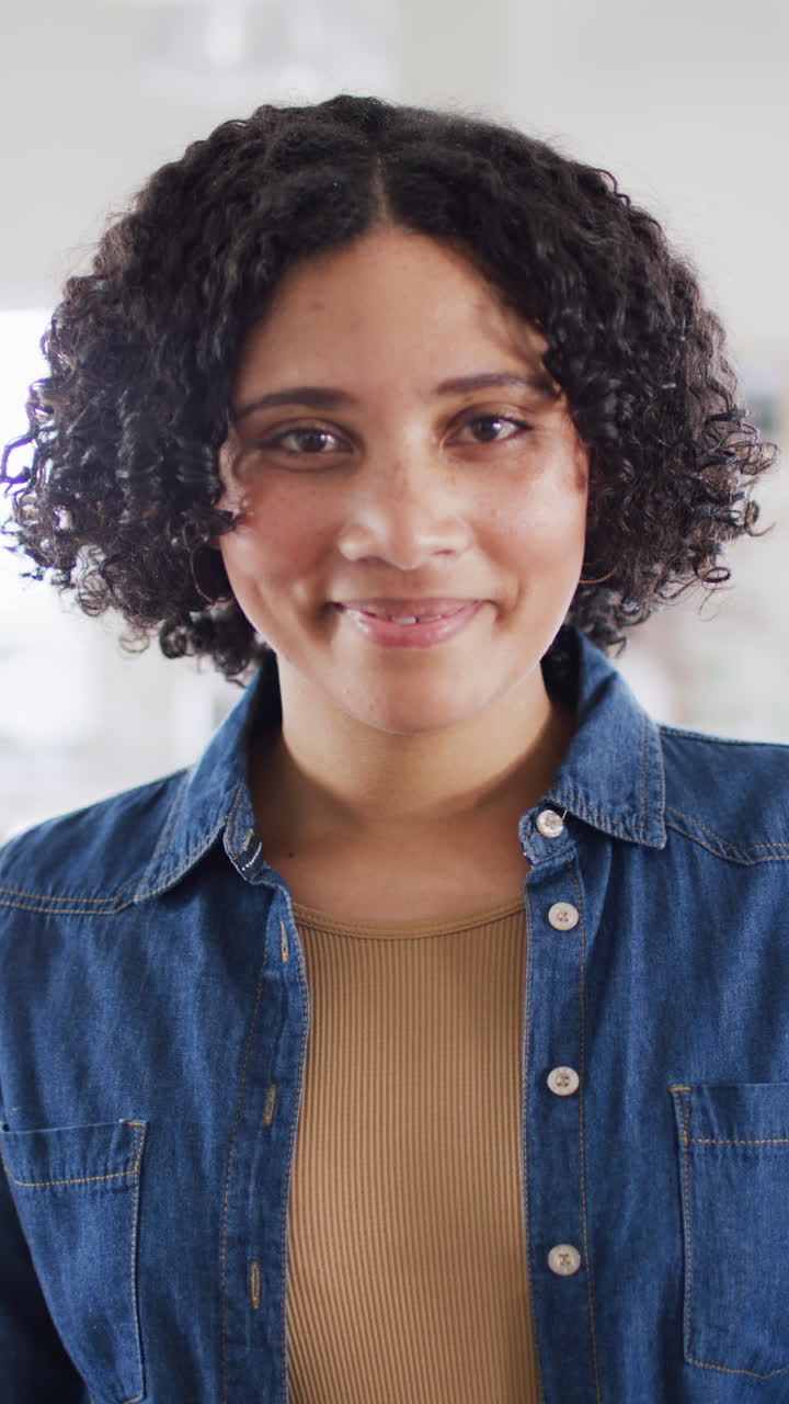 Vertical video portrait of happy biracial woman at home smiling to camera, in slow motion