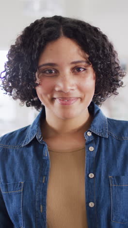 vertical video portrait of happy biracial woman at home smiling to camera, in slow motion