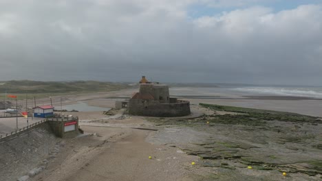 Drone-Volando-Hacia-El-Fuerte-Histórico-En-Ambleteuse-Francia-Durante-La-Marea-Baja