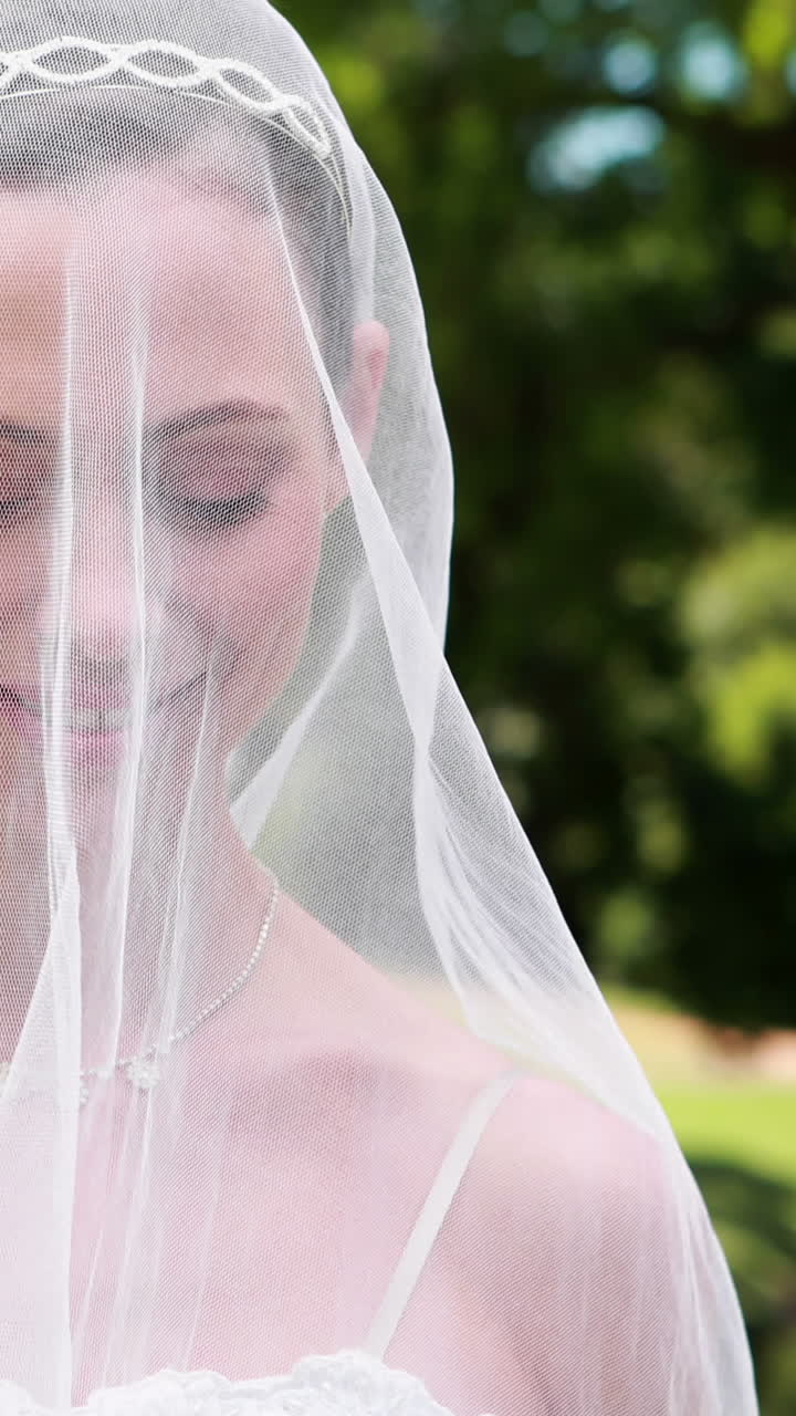 Bella sposa che sorride alla fotocamera con il velo sul viso