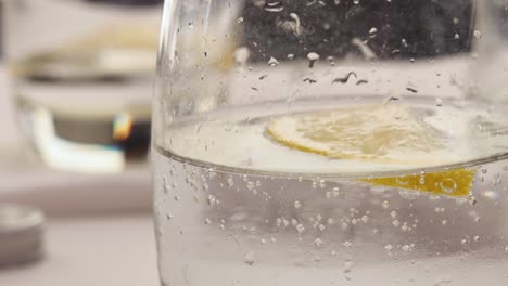 una rodaja de limón flotando en un vaso de agua con gas