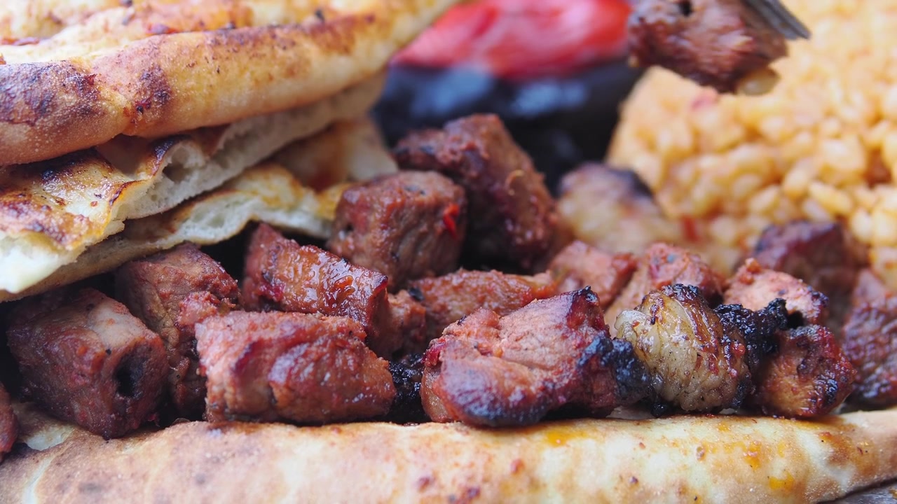 Forchetta che prende pezzi di carne grigliata da un piatto tradizionale turco