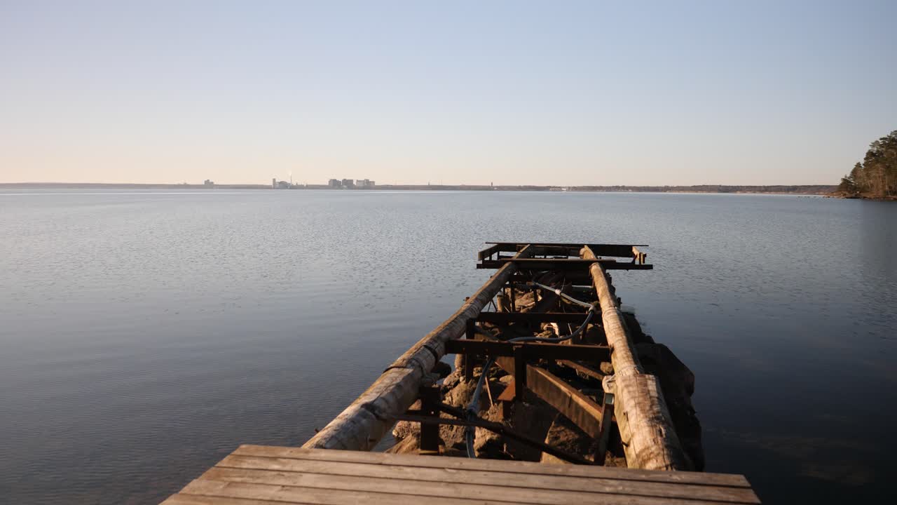 A dynamic shot of a broken jetty moving upwards from the footpath towards the open water to the horizon