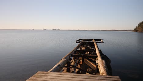 a dynamic shot of a broken jetty moving upwards from the footpath towards the open water to the horizon