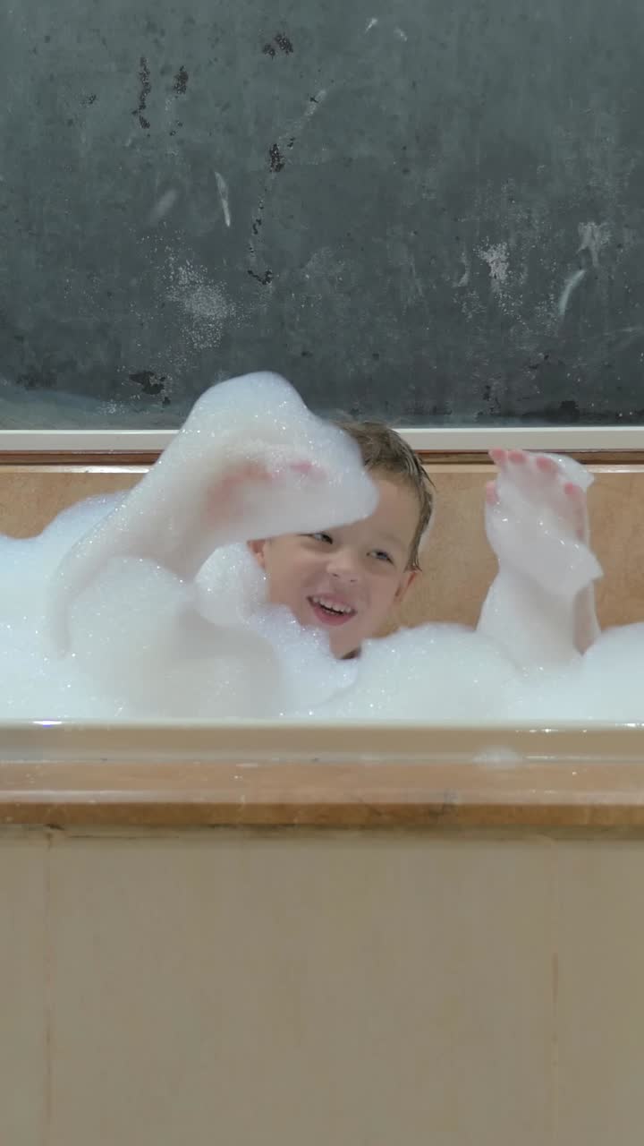 Happy Young Boy Playing with Bubbles in Bathtub