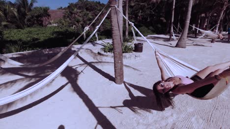 caucasian female swinging on a white hammock at the beach