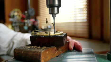 horologist using drill machine on a clock part