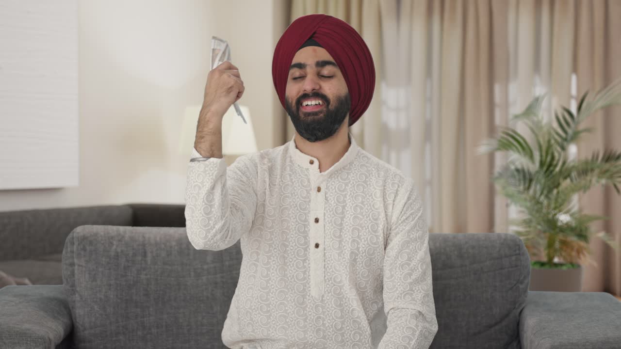 hombre indio sikh feliz usando dinero como ventilador