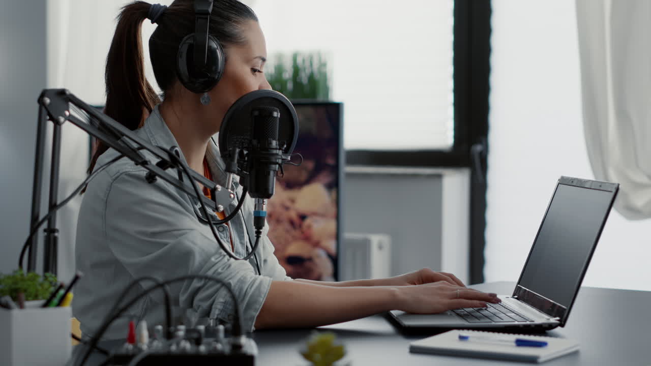 Podcast show host typing on laptop while talking to audience