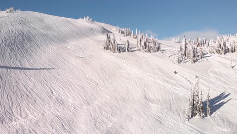 Vista-Panorámica-Aérea-De-Una-Moto-De-Nieve-Montada-En-Una-Colina-Nevada-En-Un-Día-Soleado-En-Revelstoke,-Canadá