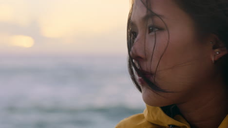 portrait-of-happy-asian-woman-enjoying-peaceful-contemplation-exploring-carefree-lifestyle-relaxing-on-beach-feeling-positive-at-sunrise