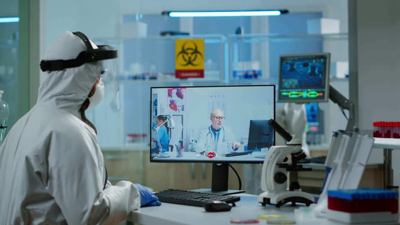 químico en traje de ppe escuchando médico profesional en llamada de video