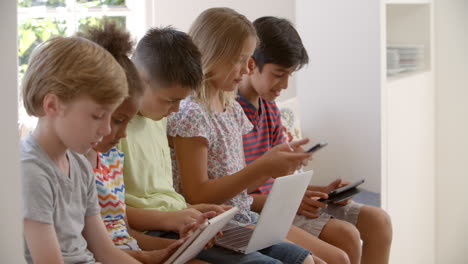 grupo de niños sentados en el asiento de la ventana y usando tecnología