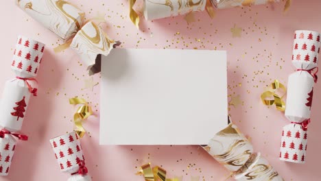 video of christmas crackers and copy space on white card and pink background