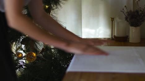 christmas tree with female hands preparing table in foreground