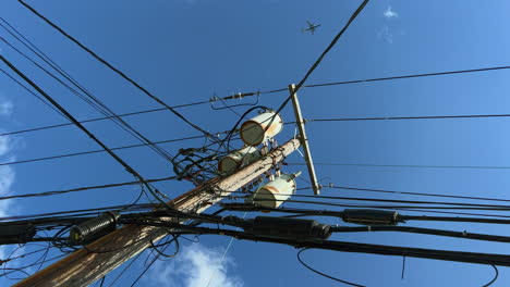 a low angle shot, looking upwards at a typical utility pole on a sunny day, with blue skies and white clouds