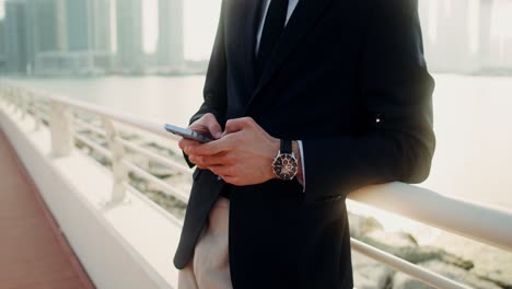 businessman using smartphone on a bridge in a city