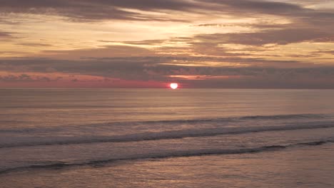 Sonnenuntergang-Am-Strand-Mit-Der-Orangefarbenen-Kugel-Am-Horizont-Und-Beruhigenden-Meereswellen,-Die-Vorbeirollen