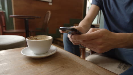 Hombre-En-La-Cafetería-Usando-El-Teléfono-Y-Tomando-Café,-Cerrar-Detalle