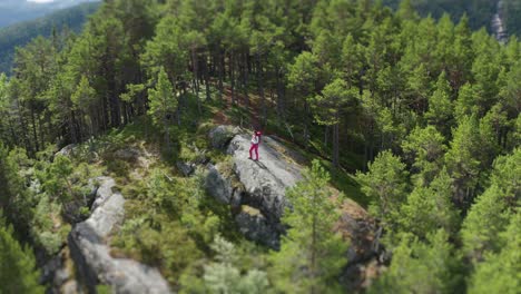 Eine-Wanderin-Mit-Schwerem-Rucksack-Auf-Dem-Rücken,-Die-Auf-Dem-Felsvorsprung-Inmitten-Des-Bewaldeten-Plateaus-Steht-Und-Die-Aussicht-Auf-Das-Weite-Tal-Genießt