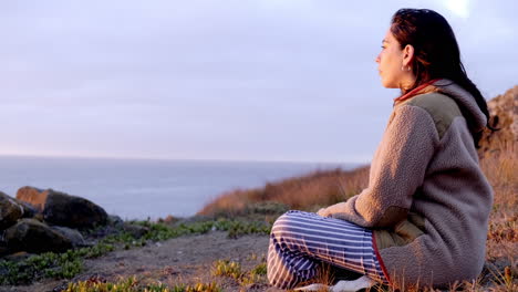 mujer viendo la puesta de sol en la playa, con una hermosa luz cálida de puesta de sol, tranquila y relajada, foto de perfil, costa de chile