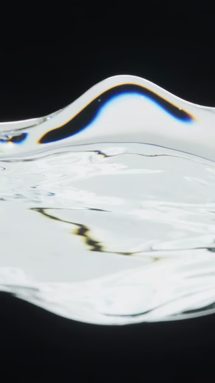 Vertical video: Forming thin film crest after pulse on black, with blue-gold rim, returning to calm