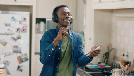 happy african american man dancing in kitchen listening to music wearing headphones having fun dance celebration enjoying weekend at home