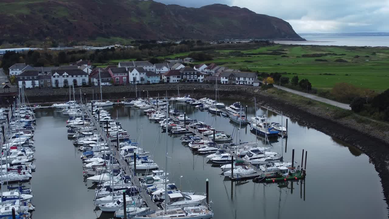 왼쪽 궤도를 위로 기울이는 산악 해안선 조감도 아래 경치 좋은 해안가 항구 아파트 마을 요트와 범선