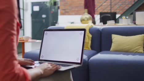 sección media de una mujer de negocios biracial que usa una computadora portátil con espacio de copia en la oficina
