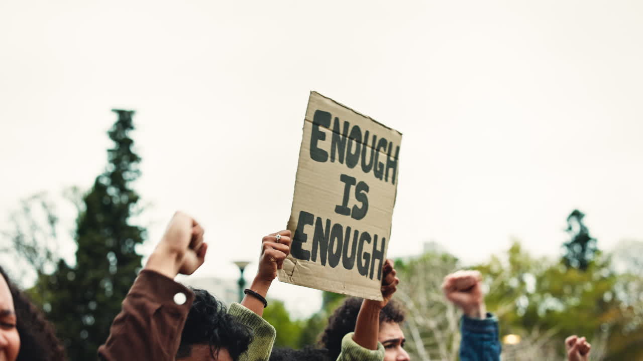 People Raising Fists and Holding "Enough Is Enough" Protest Sign