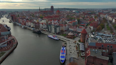 Vista-Aérea-De-Drones-Volando-Hacia-El-Casco-Antiguo-De-Gdansk,-Polonia,-Sobre-El-Río-Motlawa