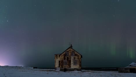 Stable shot timelapse at 25 frames per second shows a northern lights above a rusty abandoned house