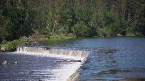 wide shot of a small weir at a river