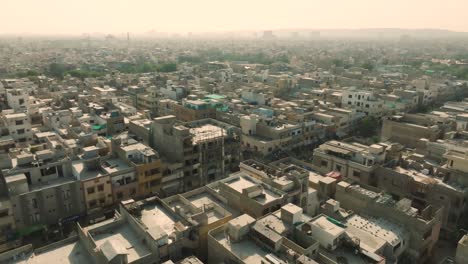 drone aéreo moviéndose hacia atrás disparado sobre la ciudad congestionada de ancholi con filas de edificios en karachi, pakistán durante el día