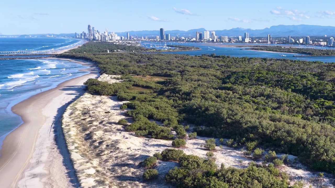 Ripresa aerea con drone di dune di sabbia, foresta e onde oceaniche a South Stradbroke Island, Australia