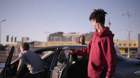 felices y sonrientes dos parejas jóvenes multirraciales salen del auto y caminan por la zona de estacionamiento cerca de los centros comerciales alrededor