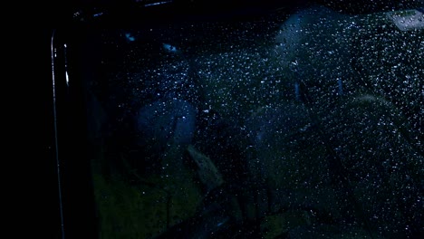 gotas de lluvia que caen en el parabrisas durante la noche