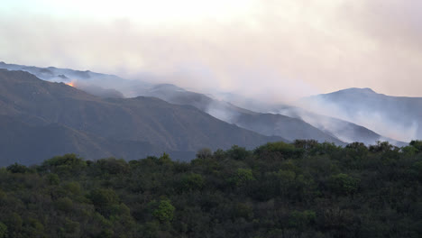 Timelapse-of-a-mountain-fire-with-flames-and-smoke-and-forest-below-in-the-valley