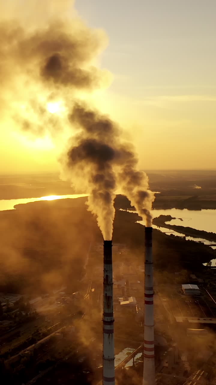 Fuming pipe power plant. Industrial landscape of manufacturing factory buildings with smoke pipes Vertical video