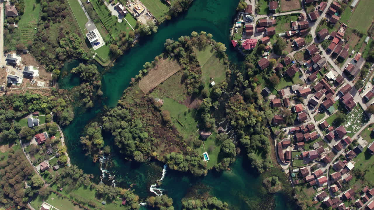Drone footage showing a heart shaped curve of the Una River surrounded by greenery, fields and houses near Bihac, Bosnia and Herzegovina. Clear turquoise water and vibrant landscape seen from above