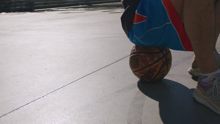 toma de detalle de un joven en una cancha de baloncesto en la calle con un sol de puesta de sol con una luz agradable, en barcelona, españa