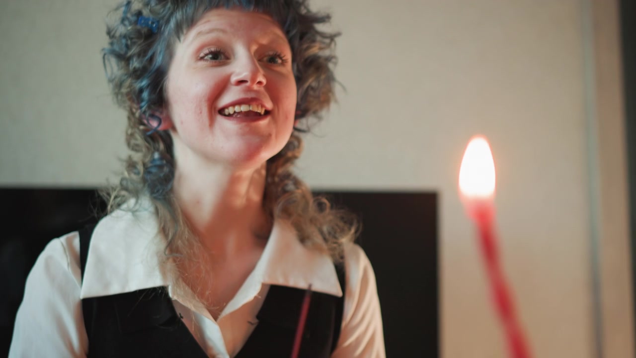 Gesti delicati illuminano un accogliente spazio interno. Immagini serene di un lettore sorridente con fiamme e incenso. Individuo allegro con capelli ricci offre storie confortanti e gesti calorosi