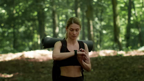 woman checking smartwatch during outdoor activity in forest